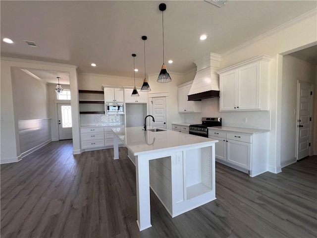 kitchen with sink, stainless steel appliances, an island with sink, white cabinets, and custom range hood