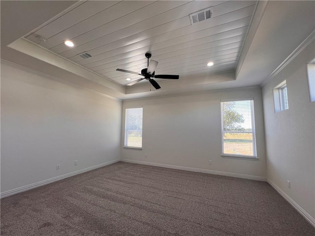 carpeted empty room featuring a raised ceiling, a wealth of natural light, crown molding, and ceiling fan