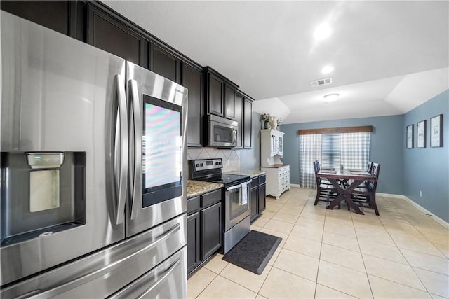 kitchen with light stone countertops, light tile patterned floors, backsplash, and appliances with stainless steel finishes