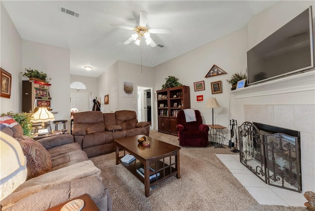 carpeted living room featuring a tile fireplace and ceiling fan