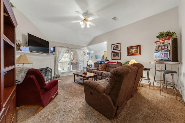 carpeted living room with a tiled fireplace, vaulted ceiling, and ceiling fan