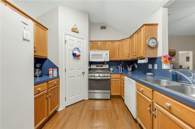 kitchen with vaulted ceiling, sink, white appliances, and light hardwood / wood-style floors