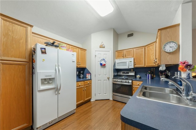 kitchen with vaulted ceiling, sink, white appliances, and light hardwood / wood-style flooring