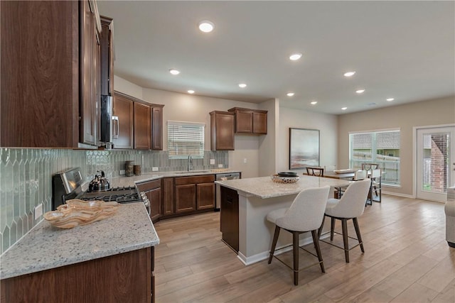 kitchen with light stone counters, stainless steel gas range, a kitchen island, and decorative backsplash