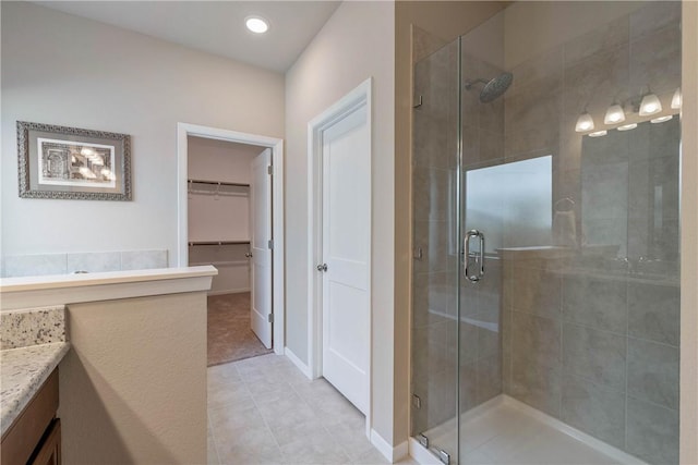 full bathroom featuring tile patterned floors, a shower stall, vanity, and a spacious closet