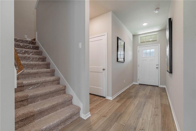 entrance foyer featuring baseboards, light wood finished floors, and stairs