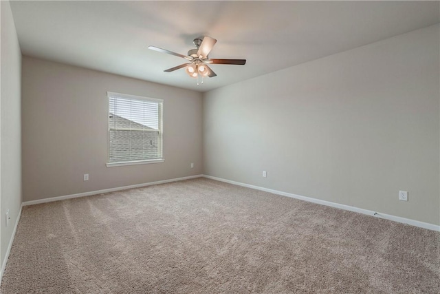 carpeted spare room with a ceiling fan and baseboards