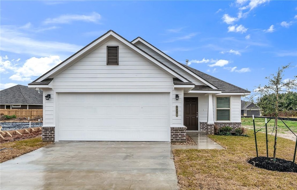 view of front of home featuring a front lawn, brick siding, concrete driveway, an attached garage, and fence