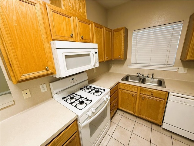 kitchen featuring light countertops, white appliances, a sink, and brown cabinets