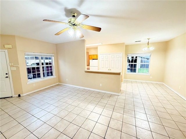 spare room with ceiling fan with notable chandelier, light tile patterned floors, visible vents, and baseboards