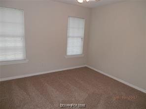 empty room with baseboards and dark carpet