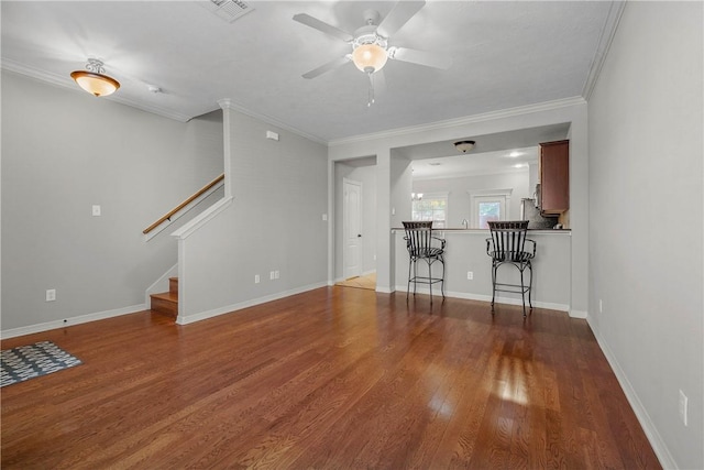 unfurnished living room featuring wood finished floors, visible vents, baseboards, stairs, and crown molding