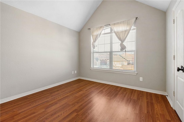 unfurnished room featuring baseboards, wood finished floors, and vaulted ceiling