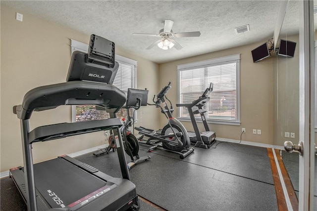 workout room with ceiling fan, visible vents, baseboards, and a textured ceiling