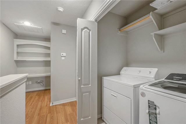 laundry room with laundry area, separate washer and dryer, light wood-type flooring, and baseboards