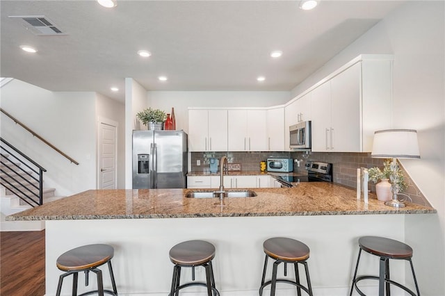 440 William D Fitch Pkwy, College Station, TX 77845 - kitchen with appliances with stainless steel finishes, a sink, a peninsula, light stone counters, and backsplash