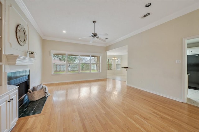 living room with a tiled fireplace, ceiling fan, hardwood / wood-style floors, and crown molding