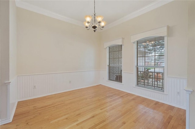 spare room featuring crown molding, light wood-type flooring, and a notable chandelier