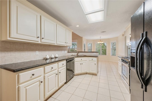 kitchen featuring kitchen peninsula, sink, black appliances, hanging light fixtures, and light tile patterned flooring