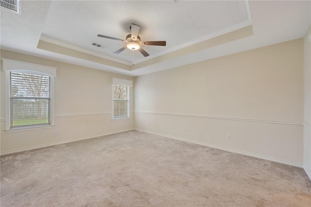 carpeted spare room with a raised ceiling, ceiling fan, and crown molding