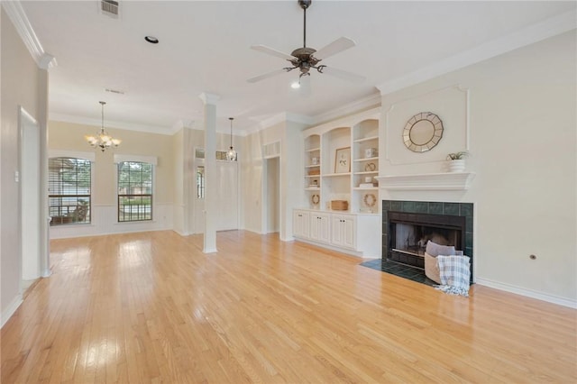 unfurnished living room with ceiling fan with notable chandelier, crown molding, light hardwood / wood-style flooring, built in features, and a tiled fireplace