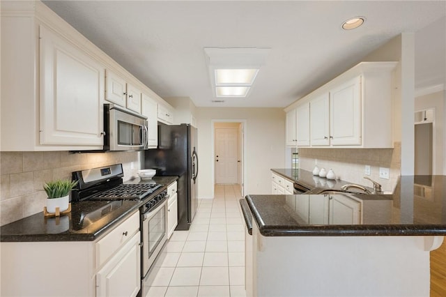 kitchen with kitchen peninsula, white cabinets, light tile patterned floors, and appliances with stainless steel finishes