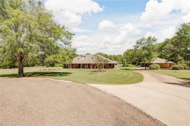 view of front of property featuring brick siding, driveway, and a front yard