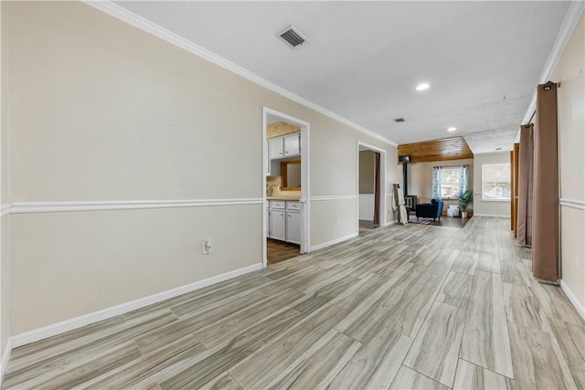 interior space featuring light hardwood / wood-style floors, a wood stove, and ornamental molding