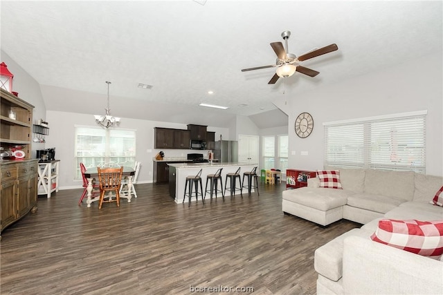 living room featuring ceiling fan with notable chandelier, dark hardwood / wood-style flooring, and vaulted ceiling