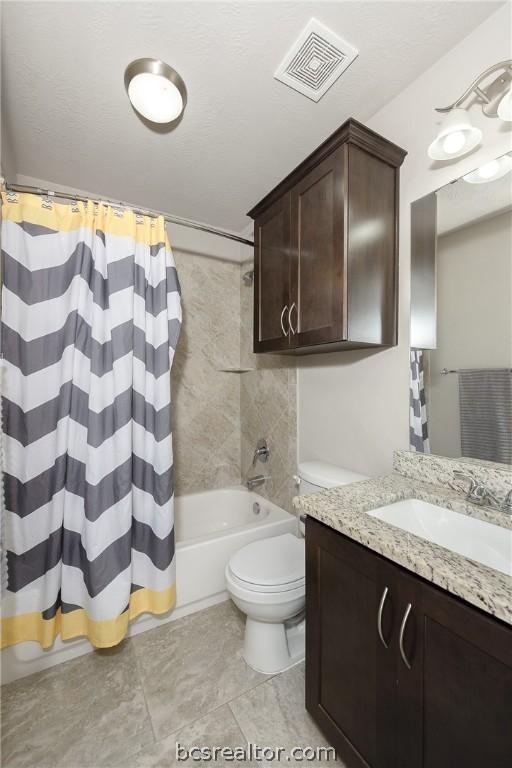 full bathroom with shower / bath combo, tile patterned flooring, a textured ceiling, toilet, and vanity