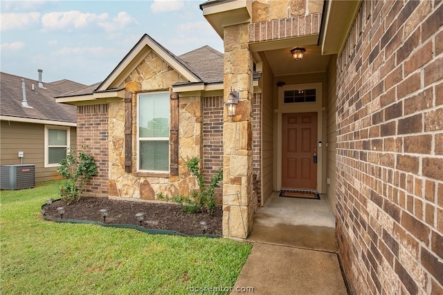 doorway to property with central air condition unit and a yard