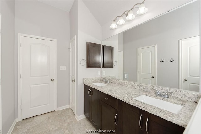 bathroom with tile patterned flooring, vanity, and lofted ceiling