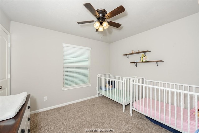 carpeted bedroom with ceiling fan and a crib