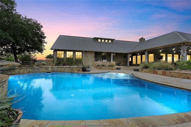 pool at dusk featuring a patio