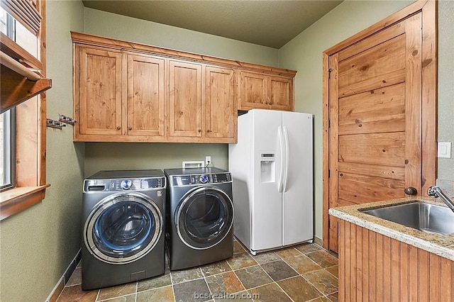 washroom with washer and dryer, cabinets, and sink