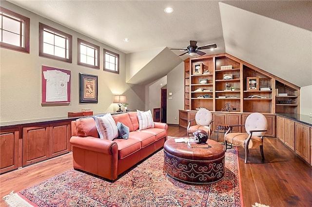 living room featuring ceiling fan, light wood-type flooring, a textured ceiling, and lofted ceiling