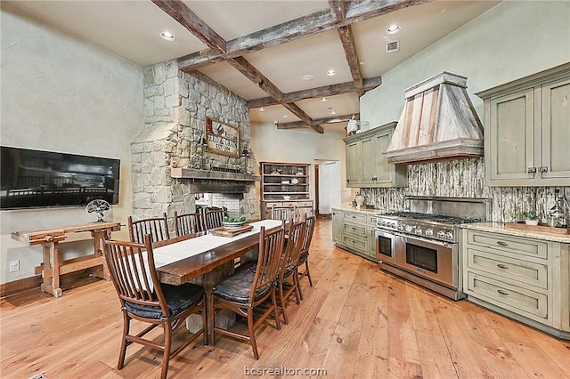 kitchen featuring light wood-type flooring, premium range hood, range with two ovens, green cabinetry, and beamed ceiling