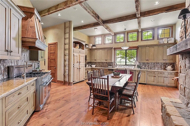 kitchen featuring beamed ceiling, light wood-type flooring, stainless steel range, and tasteful backsplash