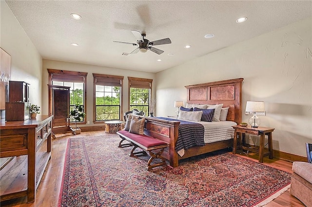 bedroom with ceiling fan, hardwood / wood-style floors, and a textured ceiling