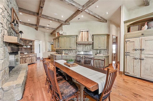 dining space featuring beamed ceiling, a high ceiling, and light wood-type flooring