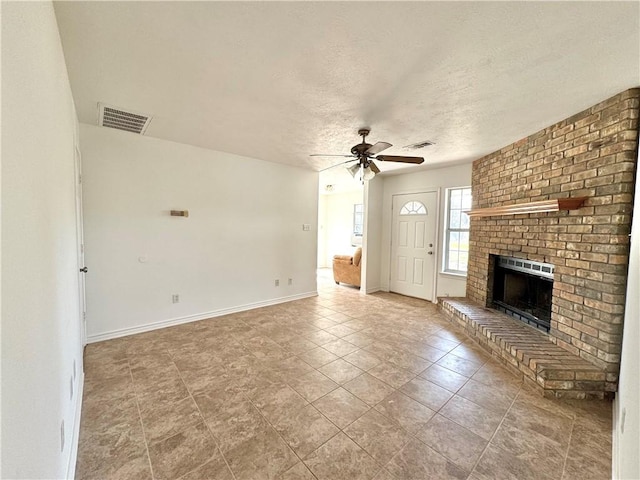 unfurnished living room featuring baseboards, visible vents, ceiling fan, a textured ceiling, and a fireplace