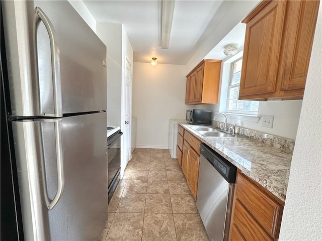 kitchen with brown cabinets, light tile patterned floors, stainless steel appliances, a sink, and baseboards