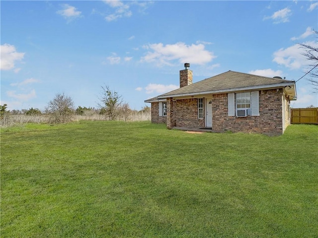 rear view of property with brick siding, a yard, a chimney, fence, and cooling unit