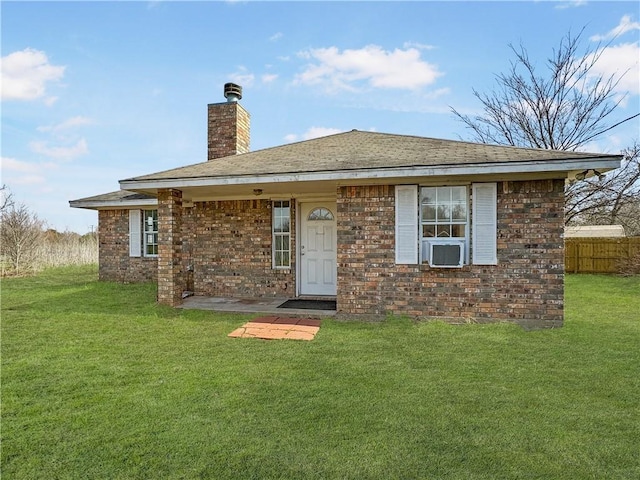 rear view of house with cooling unit, brick siding, fence, a yard, and a chimney