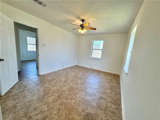 spare room with visible vents, plenty of natural light, baseboards, and ceiling fan