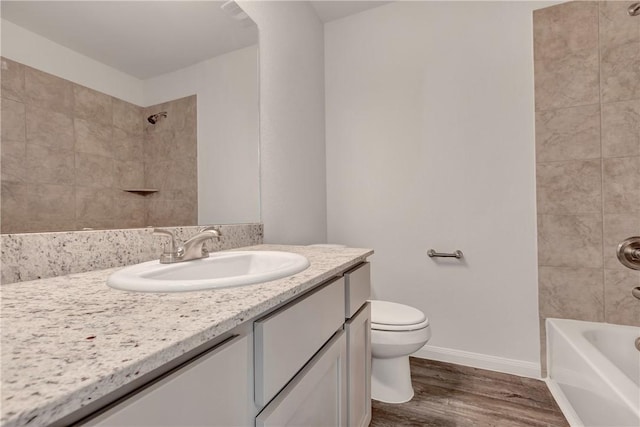 full bathroom with tiled shower / bath, hardwood / wood-style floors, vanity, and toilet