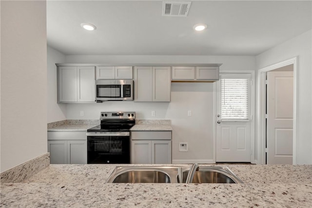 kitchen with gray cabinets, light stone counters, sink, and appliances with stainless steel finishes