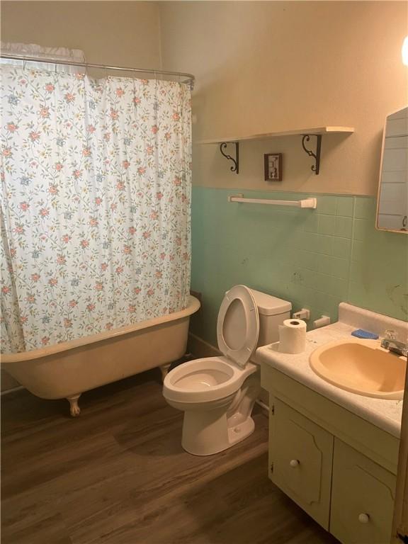 5225 Colorado St, Richards, TX 77873 - bathroom with wood finished floors, vanity, a tub to relax in, wainscoting, and a shower with curtain
