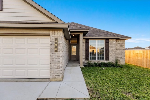 view of exterior entry featuring a yard and a garage