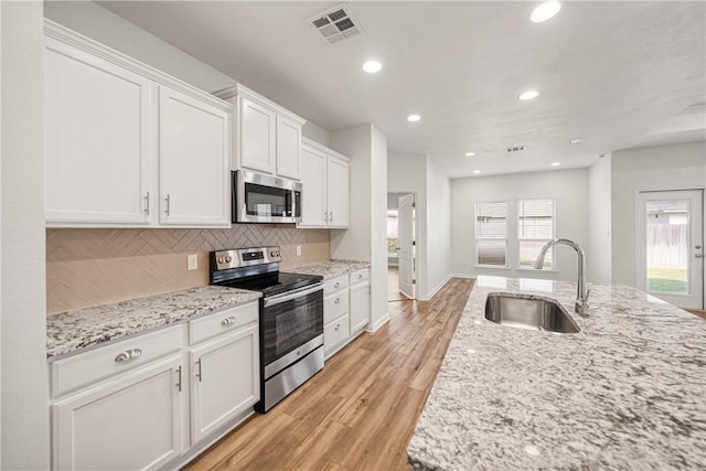 kitchen with white cabinets, sink, light wood-type flooring, light stone counters, and stainless steel appliances